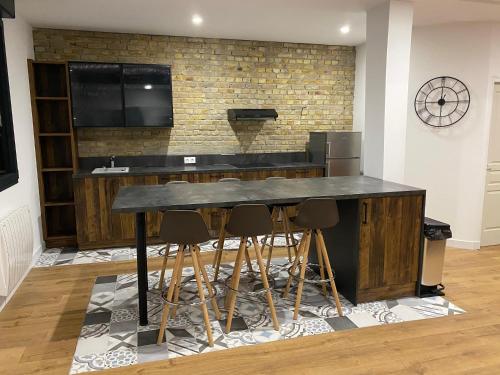 une cuisine avec un bar avec des tabourets et une télévision dans l'établissement La Sècherie de Waldam pour 4 personnes, à Oye-Plage