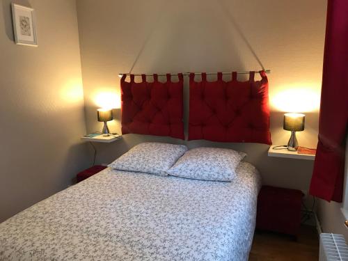 een slaapkamer met een bed met een rood hoofdeinde en 2 lampen bij Les logettes in Honfleur