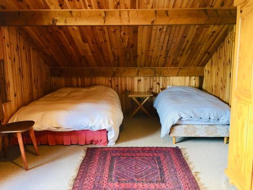 - 2 lits dans une chambre en bois avec un tapis dans l'établissement Chalet du Meilly, à Saint-Gervais-les-Bains