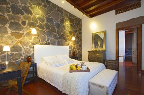 - une chambre avec un lit et un mur en pierre dans l'établissement Casa Rural Hero, à Tías