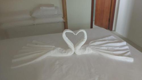 a white bed with a heart made out of towels at Pousada Bahia-Nova Caraíva in Caraíva