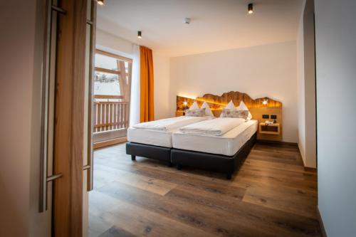 a bedroom with a large bed and a balcony at Hotel Gran Pre in San Vigilio Di Marebbe