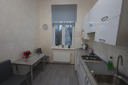 een keuken met witte kasten en een tafel en een raam bij New cozy apartment near Opera House and “Malevich” in Lviv