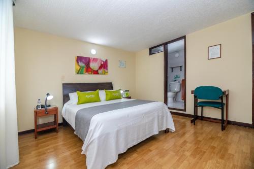 - une chambre avec un grand lit et une chaise bleue dans l'établissement Ayenda Aragon, à Manizales