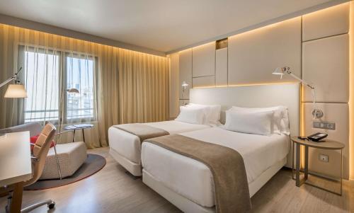 a hotel room with a large bed and a large window at NH Collection Lisboa Liberdade in Lisbon
