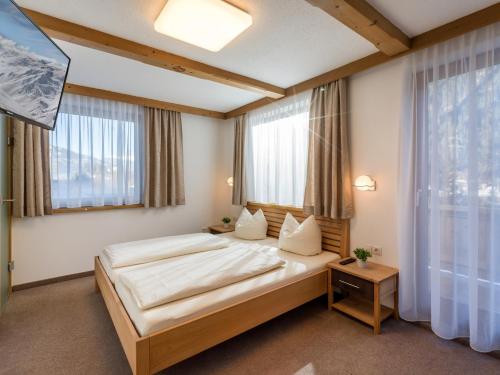 a bedroom with a large bed and two windows at Ferienhaus Zimmereben in Mayrhofen