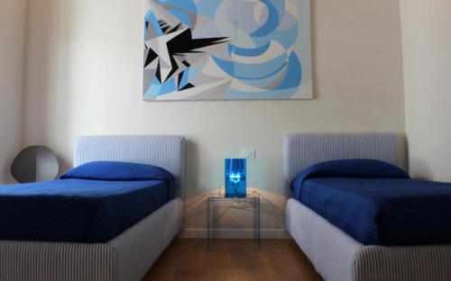 a room with two beds and a painting on the wall at Dimora di Charme Cassaro 168 in Marsala