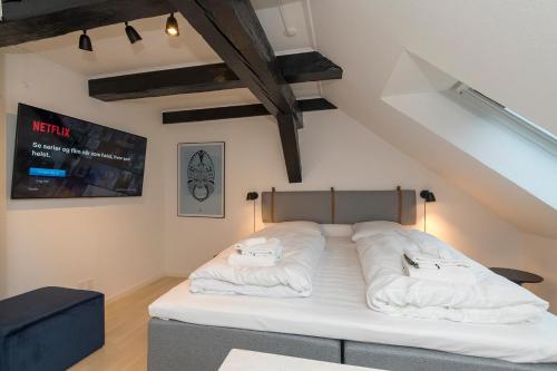 een bed met witte kussens in een kamer bij Modern Luxury Penthouse in Sønderborg
