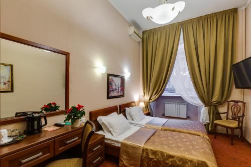 a hotel room with a bed and a desk and a mirror at Solo Prima in Saint Petersburg