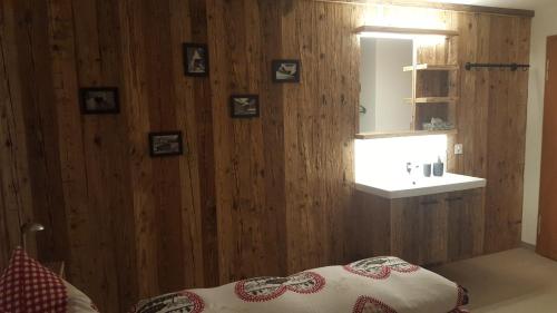 アローザにあるChalet Waldperleの木製の壁のベッドルーム(鏡、ベッド付)