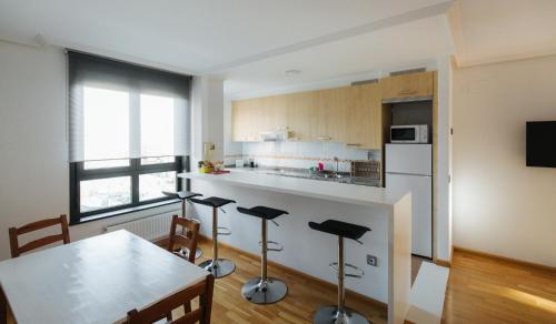 uma cozinha com uma mesa e bancos num quarto em Apartamento MyM2 em Gijón