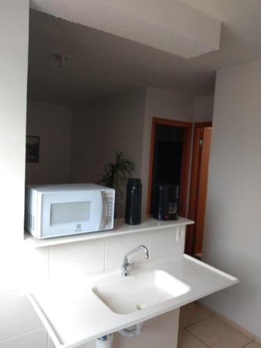 a kitchen with a sink and a microwave on a shelf at Apartamento Gaia in Campos dos Goytacazes