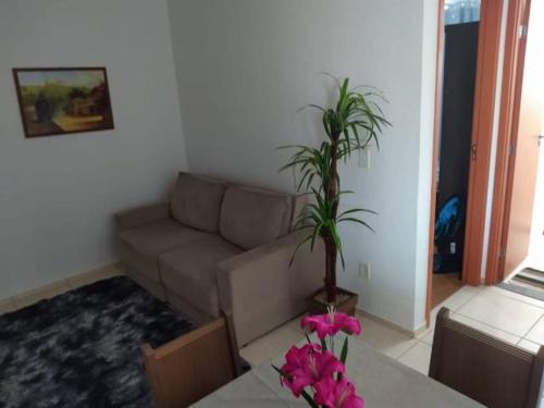 uma sala de estar com um sofá e uma mesa com flores cor-de-rosa em Apartamento Gaia em Campos dos Goytacazes
