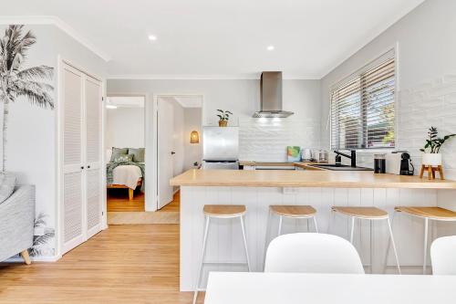 a kitchen with a counter and stools in a room at Sanbis Cabin - hidden boutique retreat, sea views in Aldinga Beach
