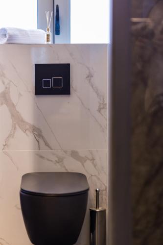 a black toilet in a bathroom with a marble wall at ASKLIPIOS LUXURY SUITE in Tríkala