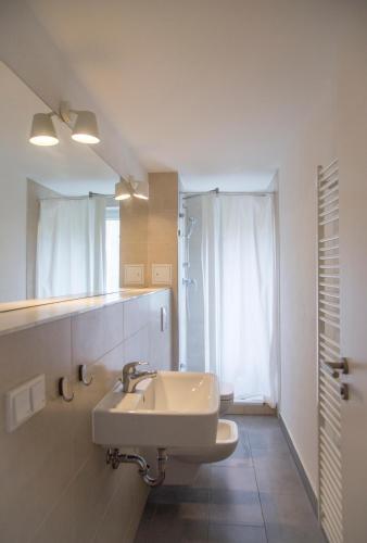 a white bathroom with a sink and a mirror at Madflats Hotel-Apartments S-Bahn Friedenau in Berlin