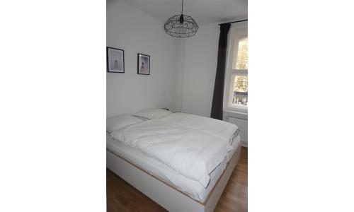 a bedroom with a bed with white sheets and a window at Madflats Hotel-Apartments S-Bahn Friedenau in Berlin