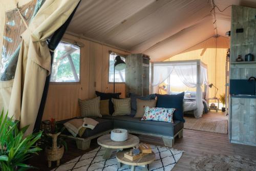 a living room with a couch and a bed at Castlemaine Gardens Luxury Safari Tents in Castlemaine