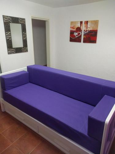 a purple couch in a room with two pictures at Departamentos Miramar in Miramar