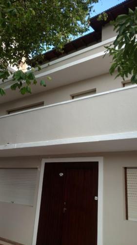 a white house with a brown door on it at Departamentos Miramar in Miramar