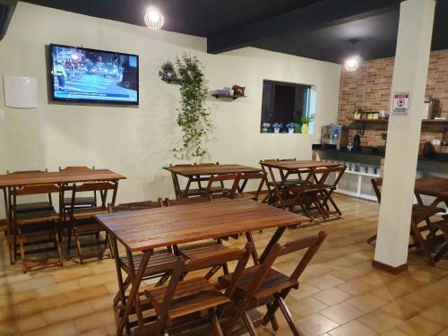 un restaurante con mesas de madera y TV en la pared en Pousada Mar e Moto, en Guaratuba