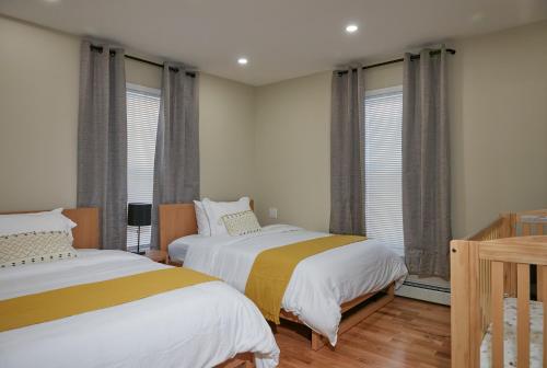 two beds in a room with windows and wooden floors at Chateau Lodge - Ski Shandaken, Hunter, Catskills, Windham, Belleayre in Shandaken