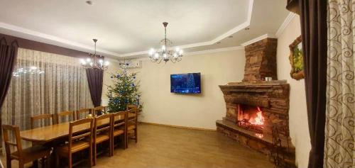 a dining room with a fireplace and a table and a christmas tree at Complex MAYARIV in Makariv