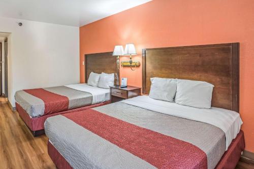 two beds in a hotel room with orange walls at Motel 6-Levittown, PA - Bensalem in Levittown