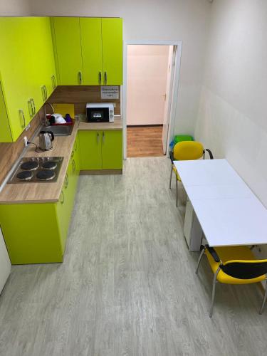 Una cocina con gabinetes verdes y una mesa y sillas. en Хостел Мажор, en Járkov