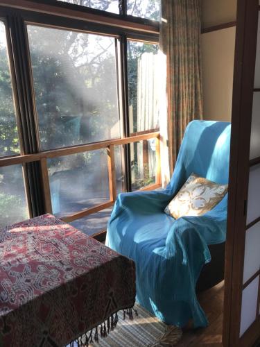 Cette chambre dispose d'une chaise et d'une grande fenêtre. dans l'établissement ＯＫＵＮＯ ＩＥ, à Oshima