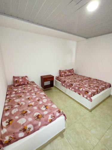 a bedroom with two beds and a night stand at Hotel Central Fusa in Fusagasuga