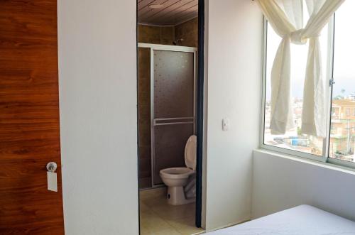 a bathroom with a toilet and a window at Hotel Central Fusa in Fusagasuga