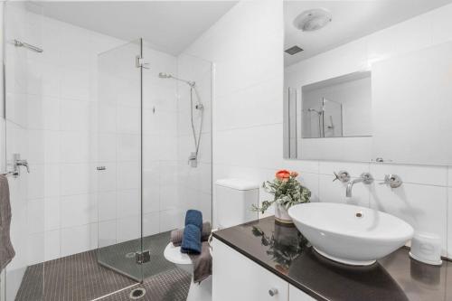 a white bathroom with a sink and a shower at A Cozy & Spacious Apt for 6 Next to Darling Harbour in Sydney