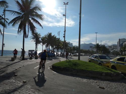 a person riding a bike on a sidewalk next to the ocean at Arpoador Premium Suítes in Rio de Janeiro