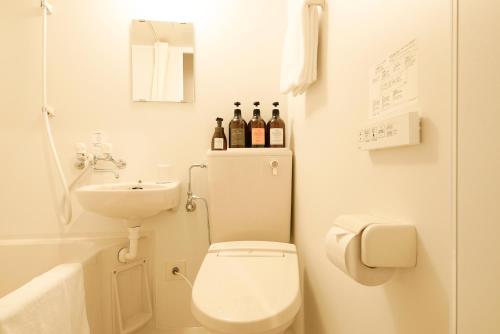 a bathroom with a toilet and a sink and bottles of wine at Hotel R9 Sano Fujioka in Sano