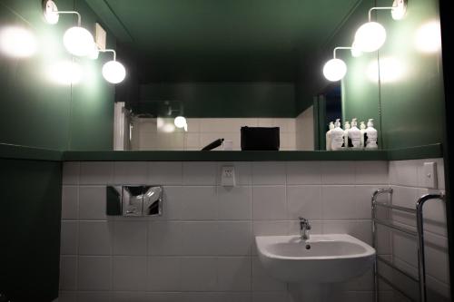 a bathroom with a sink and a mirror and lights at The Central Hotel Queenstown, A Naumi Chapter in Queenstown