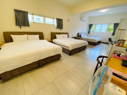 a hotel room with two beds and a desk at Taitung Crabs House in Chenggong