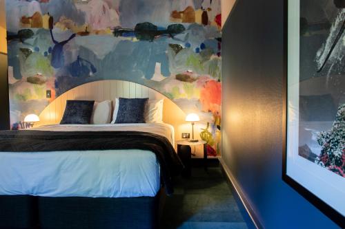 a bedroom with a large bed with a painting on the wall at The Central Hotel Queenstown, A Naumi Chapter in Queenstown
