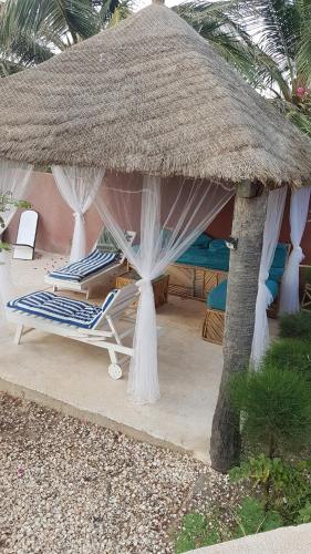 a straw umbrella and lounge chairs in a resort at la villa sur la plage in Palmarin