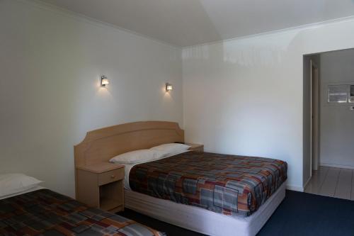 Nunawading Motor Inn في Nunawading: غرفة نوم صغيرة بسريرين وموقف ليلي