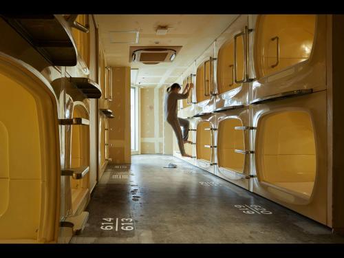 a man standing in a laundry room with washing machines at Do-C Gotanda in Tokyo