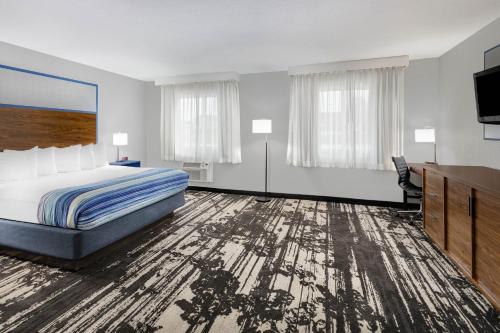 a hotel room with a bed and a flat screen tv at AmericInn by Wyndham Pella in Pella