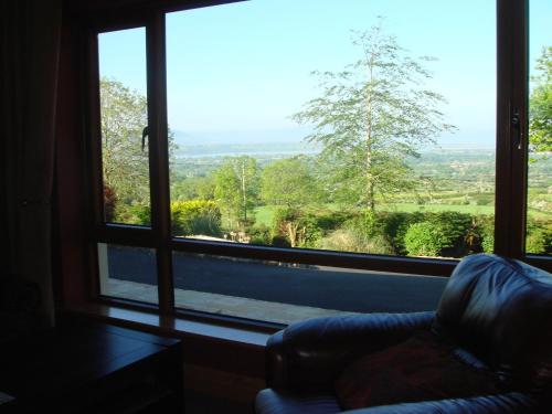a room with a couch and a large window at Benbulben Farmhouse B&B in Drumcliff