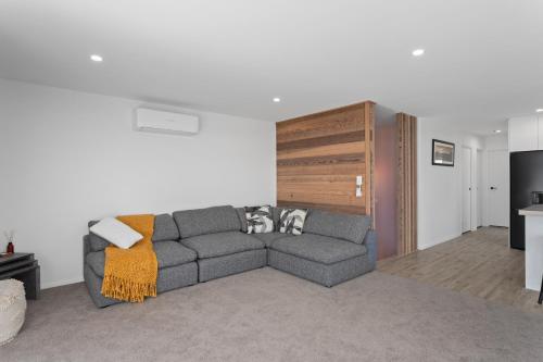 a living room with a gray couch in a room at Ohope Beachside Retreat - Ohope Holiday Home in Ohope Beach