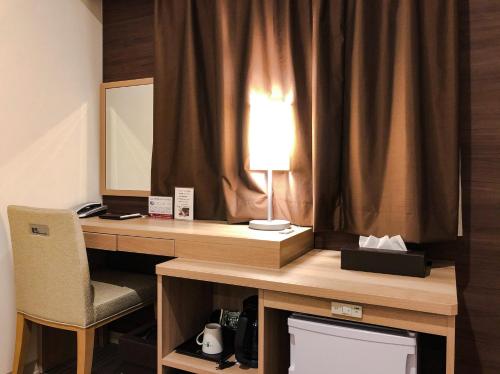 uma secretária com um candeeiro e uma cadeira num quarto em KOKO HOTEL Hiroshima Ekimae em Hiroshima