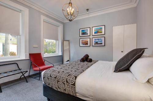 a bedroom with a large bed and a red chair at City Retreat Hobart in Hobart