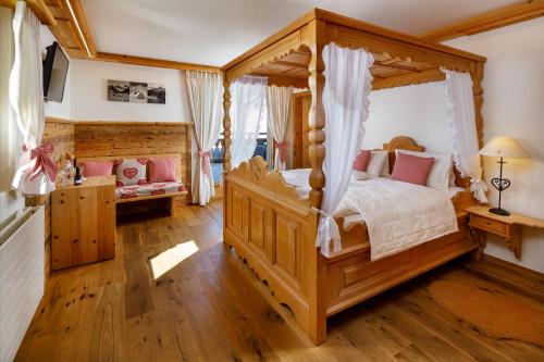 a bedroom with a wooden canopy bed with pink pillows at Walserhuus Sertig in Sertig Döfli