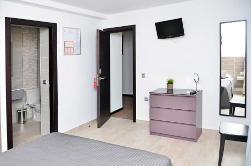 a bedroom with a purple dresser and a tv at Hostal Campito in Conil de la Frontera