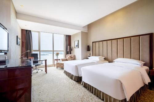 鎮江市にあるCrowne Plaza Zhenjiang, an IHG Hotelのベッド2台とテレビが備わるホテルルームです。