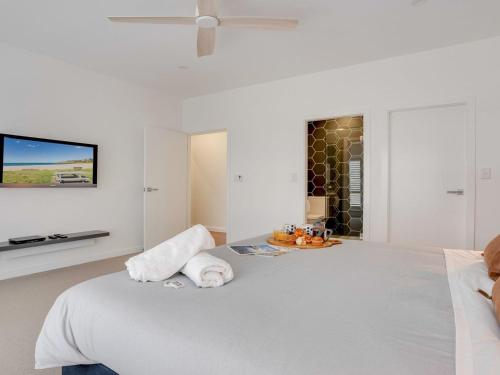 a bedroom with a large bed with a tv on the wall at Bella K in Kiama
